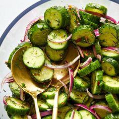 cucumber and onion salad in a glass bowl with spoons on the side