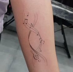 a woman's arm with musical notes on it and the word love written in cursive writing