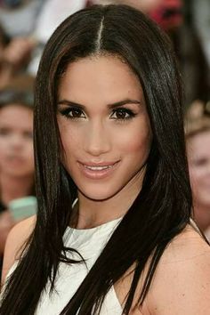 a woman with long black hair and brown eyes posing for a photo in front of a crowd