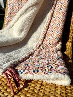 a white blanket sitting on top of a wicker chair