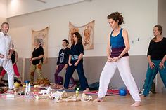 a group of people in a room with yoga mats on the floor and balls all around