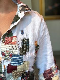 a close up of a person wearing a white shirt with colorful patches and designs on it