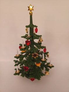 a small green christmas tree with gold stars and ornaments on it's top, against a white background