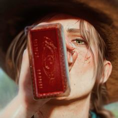 a young boy wearing a cowboy hat and holding up a red object to his face