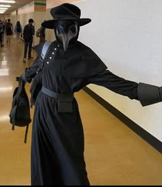 a man in a plague costume is walking down the hall with his arms out and hands outstretched