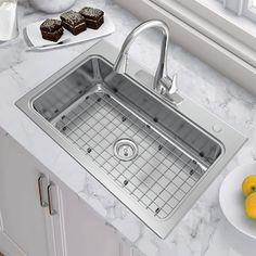 a stainless steel kitchen sink with grids on the front and side, next to some lemons