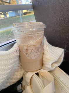 a starbucks cup sitting on top of a white purse