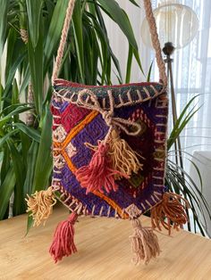 a multicolored bag with tassels hanging from it's side on a table