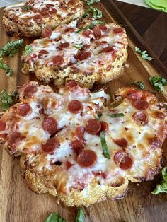 two slices of pizza sitting on top of a wooden cutting board next to green leaves