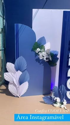 there are two blue and white paper fans on the table next to each other with flowers in them