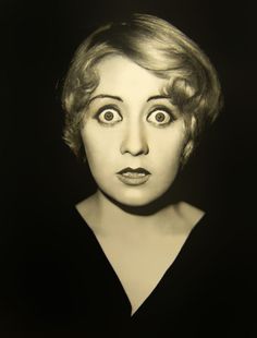 an old black and white photo of a woman making a face with her eyes wide open