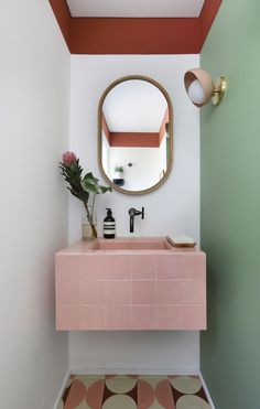 a bathroom with a pink sink and mirror