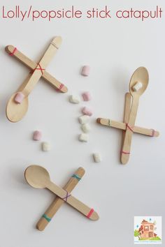 popsicle stick catapults with marshmallows scattered around them on a white surface