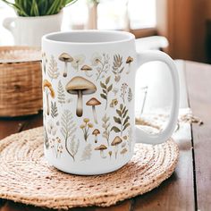 a coffee mug with mushrooms on it sitting on a place mat next to a potted plant