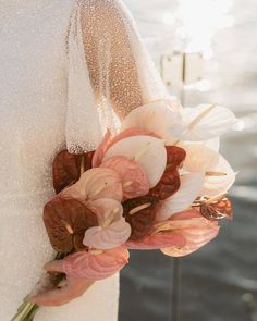 a bouquet of flowers is attached to the back of a bride's dress