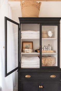 an old china cabinet with linens and towels in it