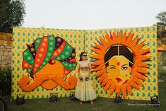 a woman standing in front of an art work on display at a wedding reception or festival