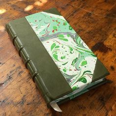 a green and white book sitting on top of a wooden table next to a knife