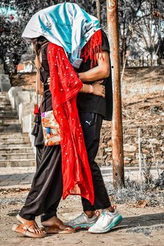 two people standing next to each other near a tree