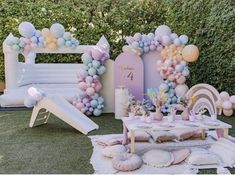 an outdoor party setup with balloons, decorations and other items in pastel colors on the grass