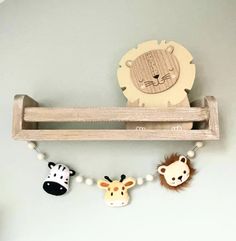 a wooden shelf with three animal magnets on it's sides and a toy lion hanging from the top