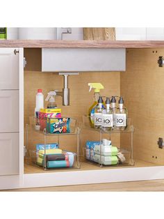 the kitchen cabinet door is open to reveal two shelves with cleaning supplies and other items