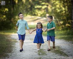 three children holding hands while walking down a dirt road