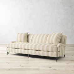 a striped couch sitting on top of a hard wood floor next to a white wall