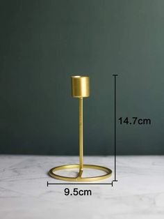 a brass candle holder on a marble table with measurements for the size and width in front of it