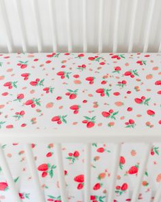 a white crib with red strawberries on it