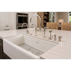 a white kitchen sink sitting under a faucet next to a stove top oven