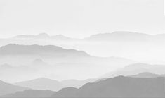 black and white photograph of mountains with fog