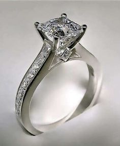 a white gold engagement ring with a princess cut diamond in the center and channel set diamonds on the side