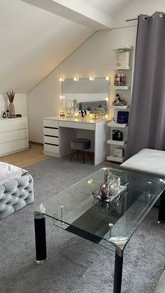 a glass table in the middle of a room with a couch and desk behind it