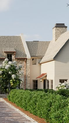 a house with white flowers in front of it and a brick walkway leading to the front door