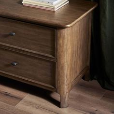 a wooden dresser with two drawers and books on top