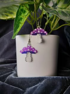 a pair of purple and white earrings sitting on top of a potted green plant