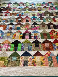 a quilted bed with many different colored houses on it