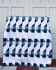 a blue and white quilt sitting on top of a wooden floor next to a garage door