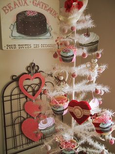 a white christmas tree decorated with cupcakes and hearts