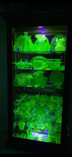 an illuminated display case filled with green glassware