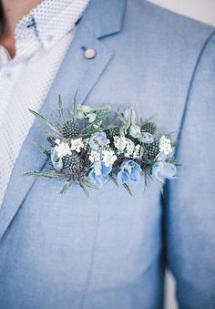 a man in a blue suit and white flowers on his lapel flower pinhole