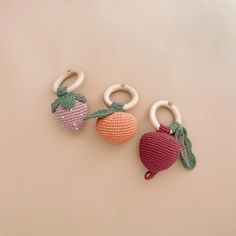 three crocheted fruit keychains on a beige background