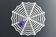 a paper spider web with purple flowers on it