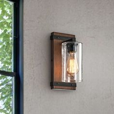 a light fixture mounted to the side of a wall with a window in the background