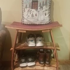 a wooden shoe rack with two pairs of shoes sitting on top of it next to a pillow