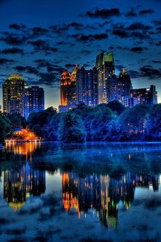 the city skyline is lit up at night, and it's reflecting in the water