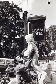 black and white photograph of people standing in front of a sign that says lymm hotel