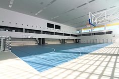 an empty basketball court in the middle of a large building with blue and yellow floors