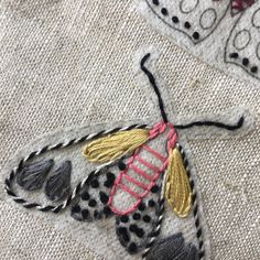 an embroidered butterfly with black and white dots on it's wings, sitting on a piece of fabric